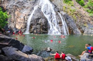 people swimming in a water fall